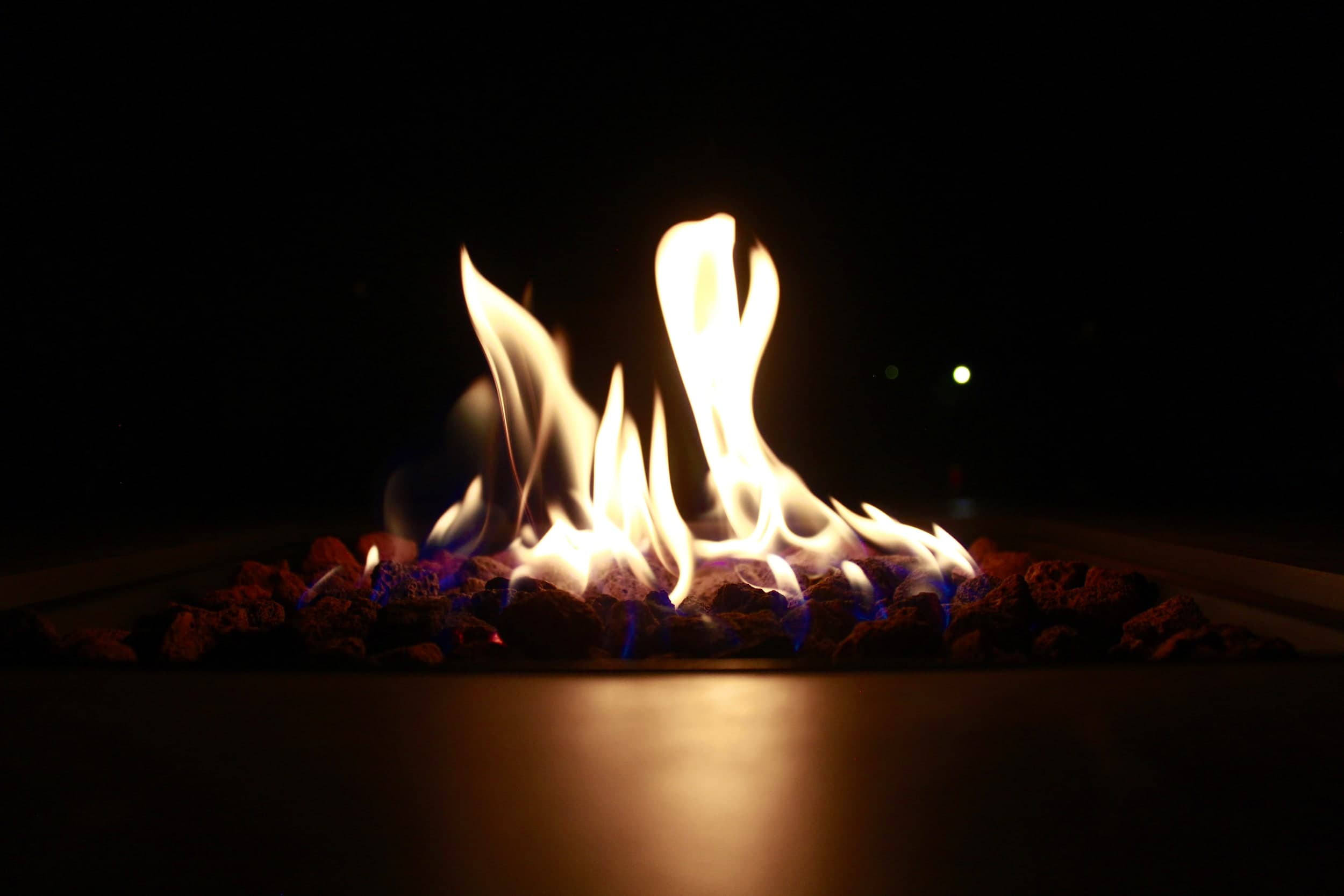 Flames rising from lava rocks in a fire pit at night