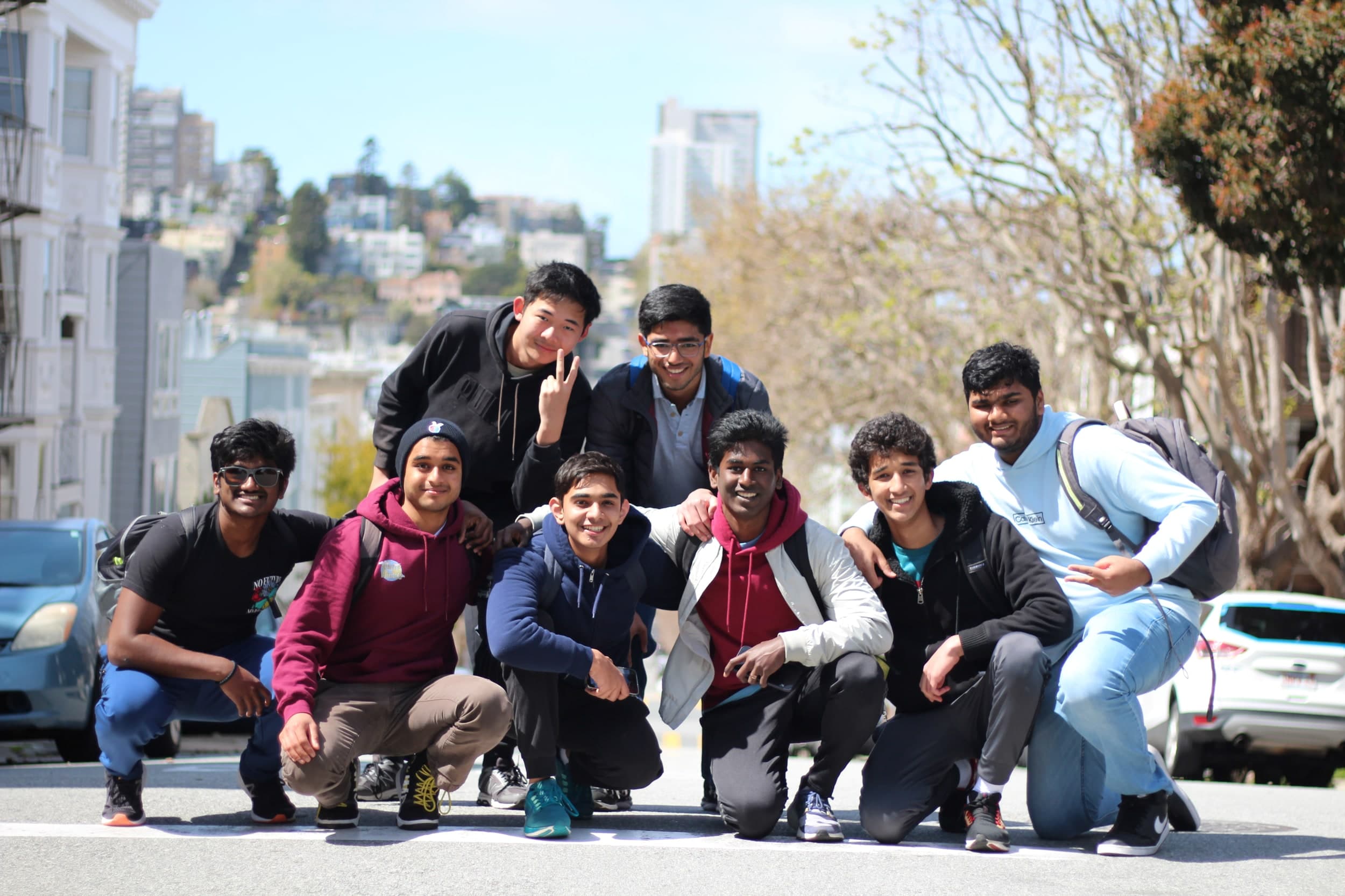 A group of eight friends posing together on a hilly city street